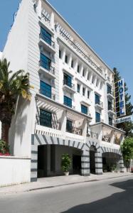 ein weißes Gebäude mit einer Palme davor in der Unterkunft Hôtel LE CONSUL in Tunis
