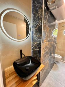 ティラナにあるBazar inn Apartaments Tiranaの黒い洗面台と鏡のあるバスルーム