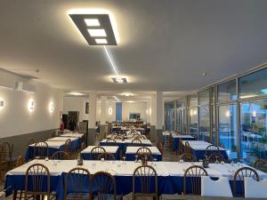 a dining room with tables and chairs with blue tablecloths at Hotel Helvetia in Grado