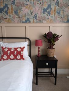 a bed with a red pillow and a table with a lamp at Rooms At The Rosebery in Norwich
