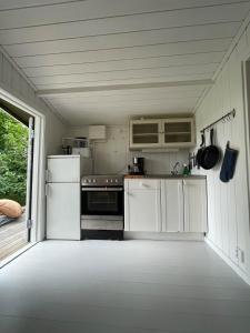 eine kleine Küche mit weißen Schränken und Geräten in der Unterkunft Cozy cottage in Stockholm Archipelago! in Muskö + 8 Fotos
