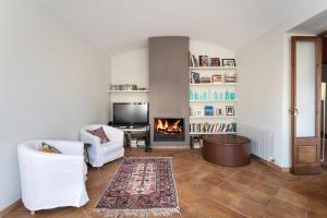 a living room with two white chairs and a fireplace at Mas Vives, exclusiva masía del siglo XV in Cabrils