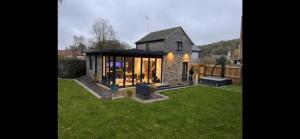 a house with a glass extension in a yard at Knatchbull Cottage in Downhead