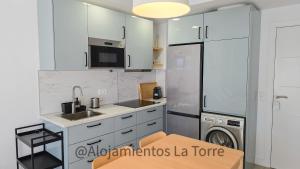 a kitchen with white cabinets and a washer and dryer at Atico Melosas - Alojamientos La Torre in Torre del Mar