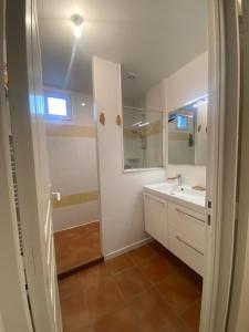 a white bathroom with a sink and a mirror at Petite maison de plein pied in Saint Malo
