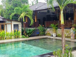 a swimming pool in front of a house at Modern Joglo Villas in Canggu 5 Bedrooms in Kerobokan