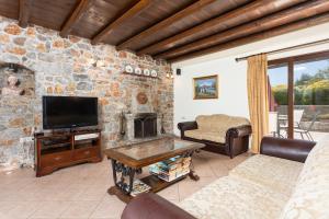 a living room with a tv and a stone wall at Villa Melina in Tavronitis