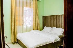 a bedroom with a bed with white sheets and a window at Elite Haven in Masaka