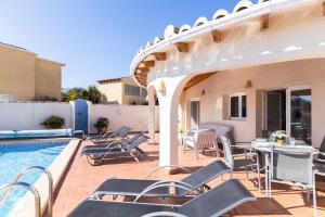 a patio with a table and chairs next to a swimming pool at Villa Diana in Benitachell