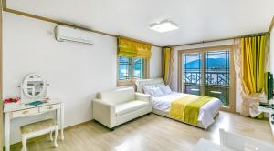 ein Schlafzimmer mit einem Bett, einem Stuhl und einem Spiegel in der Unterkunft Geojae Beach Maru Pension in Geoje + 37 Fotos