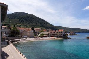 une plage avec des bâtiments et des gens sur l'eau dans l'établissement Bucol seaview suites, à Komiža