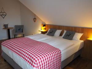 Schlafzimmer mit einem Bett mit einer roten und weißen Decke in der Unterkunft Hotel Neumaier in Xanten