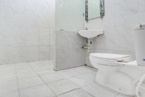 a white bathroom with a toilet and a sink at Hotel O Tegalsari Near Tunjungan Plaza in Surabaya +21 photos