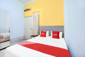 a bedroom with a bed with two red pillows at Hotel O Tegalsari Near Tunjungan Plaza in Surabaya