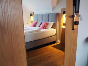 ein Schlafzimmer mit einem Bett mit roten Kissen darauf in der Unterkunft Hotel Neumaier in Xanten
