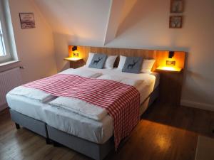 ein Schlafzimmer mit einem Bett mit einer rot-weißen Decke in der Unterkunft Hotel Neumaier in Xanten