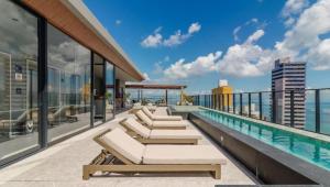 a balcony with chairs and a swimming pool on a building at Alive Corredor da Vitória - Vista Mar in Salvador