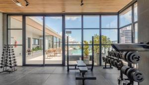 a gym with large windows and a view of a pool at Alive Corredor da Vitória - Vista Mar in Salvador