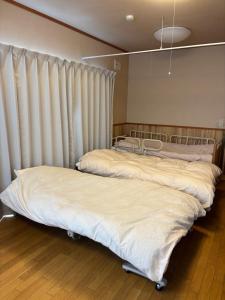 安曇野市にある安曇野温泉おもいやりの湯のカーテン付きの客室で、ベッド2台が備わります。