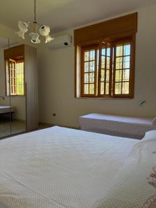 a bedroom with a large white bed and two windows at Villa Rosetta, Gallipoli tra mare e natura in Pizzo