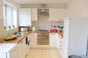 a kitchen with white cabinets and a white refrigerator at 3 Bedroom House By Trinity Stays Short Lets & Serviced Accommodation Cambridge With Free WiFi & Parking in Cambridge +19 photos