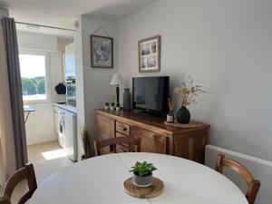 a living room with a table and a television at Ploemeur Lomener T2 Balcon Vue Mer - FR-1-349-65 in Ploemeur