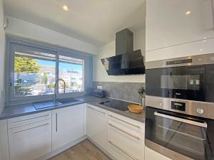 a kitchen with white cabinets and a sink and a window at Spacieux studio terrasse, mer à 700m commerces, parking privé, Wi-Fi inclu - FR-1-349-116 in Larmor-Plage