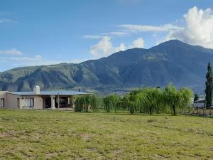 a house in a field with mountains in the background at La escondida las siringuillas in Tafí del Valle