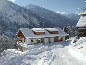 a house with snow on the roof in the mountains at Dorfblick, Ferienwohnung in Sonntag