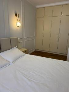 a bedroom with a white bed with a lamp and cabinets at High Stay Suite Cluj in Floreşti