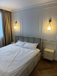 a bedroom with a large white bed with two lights at High Stay Suite Cluj in Floreşti +31 photos