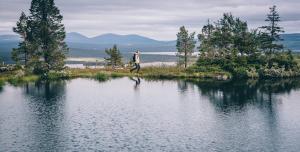 a man walking on a small island in the water at Lapland Hotels Pallas in Pallastunturi