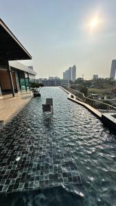 a bench sitting on the edge of a body of water at The Prim Grand Condo Wongamat N103 - Spacious apartment near the sea in Pattaya North