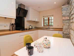 a kitchen with a white table and chairs and a counter at Honeysuckle Cottage in Somerton +12 photos