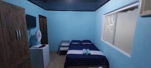 a small blue room with a bed and a window at CASA DE HOSPEDAGEM PARATY 10 MINUTOS DO CENTRO COM OPÇÕES DE CAFÉ da MANHÃ in Paraty