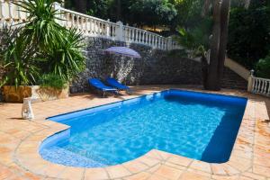 ein blauer Swimmingpool mit zwei Stühlen und einem Sonnenschirm in der Unterkunft Naturgelegenes Resort in Alboy
