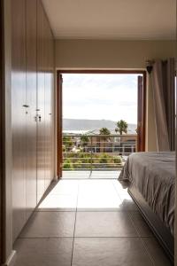 a bedroom with a bed and a large window at Serene Langebaan Getaway with Garden and pool views in Langebaan