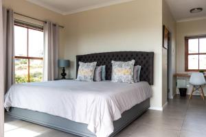 a bedroom with a large bed with white sheets and pillows at Serene Langebaan Getaway with Garden and pool views in Langebaan