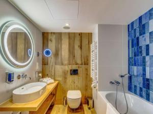 a bathroom with a tub and a toilet and a sink at Novotel Gdańsk Marina in Gdańsk
