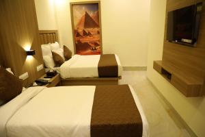 a hotel room with two beds and a flat screen tv at Hotel Bellamont in Mumbai