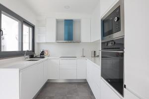 アルブフェイラにあるVilla Soares - Centro Albufeira - For Families - BY BEDZYのシンクと電子レンジを備えた白いキッチン