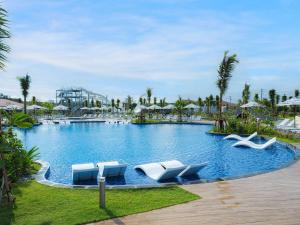 a large swimming pool with lounge chairs in a resort at Grand Mercure Okinawa Cape Zanpa Resort in Yomitan +37 photos