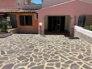 a building with a stone patio in front of a house at Casa al mare Agrustos in Agrustos
