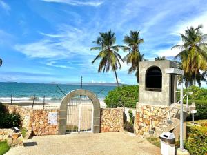 a gate to a beach with palm trees and the ocean at Apto Vip acceso a la playa in El Morro de Barcelona