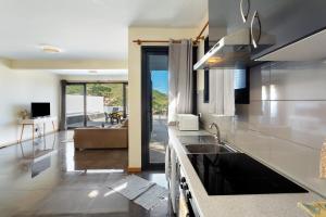 a kitchen with a sink and a living room at Casa da Pontinha in Machico
