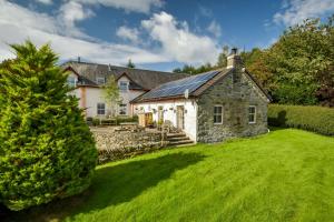 an old stone house with a green yard at Errichel House and Cottages in Aberfeldy