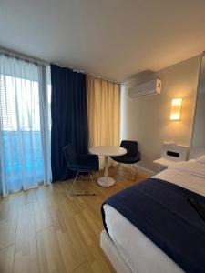 バトゥミにあるSpend Your Time in Batumi in Orbi City N3のベッド、テーブル、椅子が備わるホテルルームです。