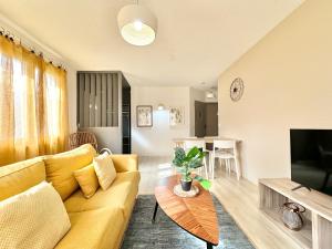 a living room with a yellow couch and a table at LO CAMIN - Cosy - Plain-Pied - Hyper Centre in Mont-de-Marsan