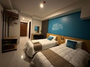 une chambre avec deux lits et un mur bleu dans l'établissement Horizons 101 Condotel, à Cebu 6 autres photos