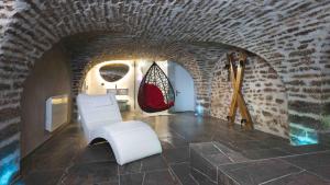 a living room with white chairs and a stone wall at La reine d'Orel - Jacuzzi privé in Besançon